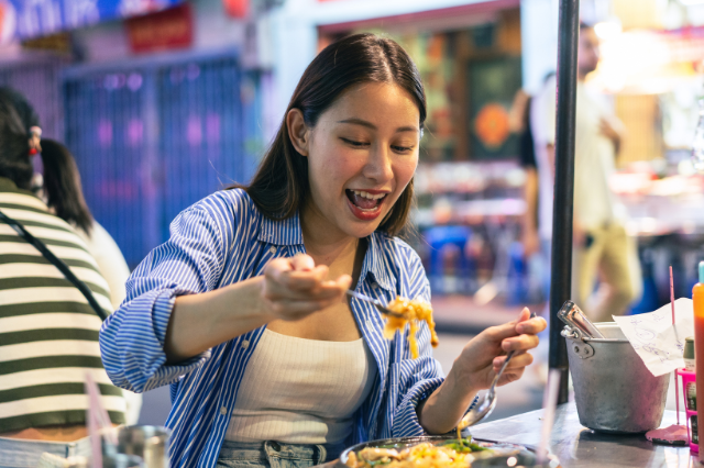 タイの屋台で食事する女性