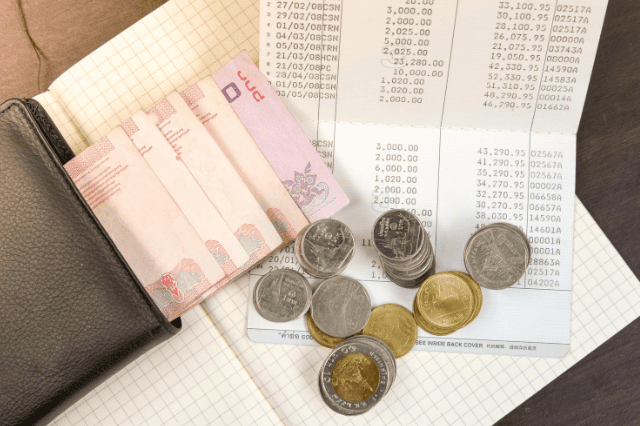 木製のテーブルの上のタイのお金と銀行の貯金通帳