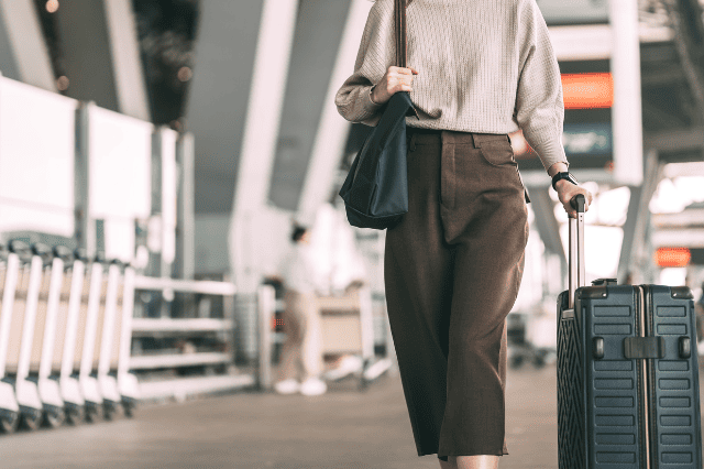 キャリーバッグを引いて空港を歩く人