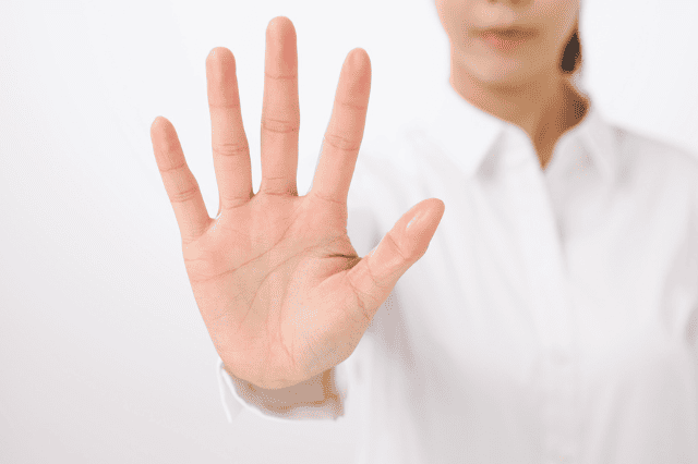 手の平を差し出して止めているサイン