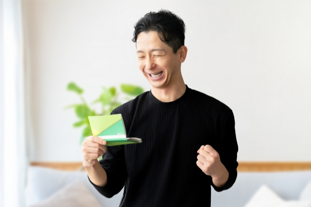 通帳を見てガッツポーズをしている男性