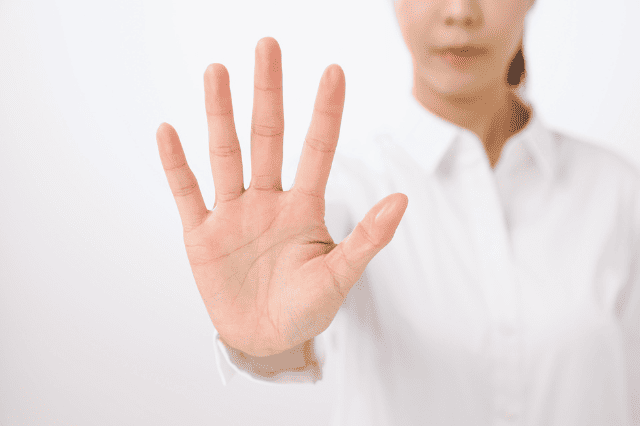 手を前に出して止める女性
